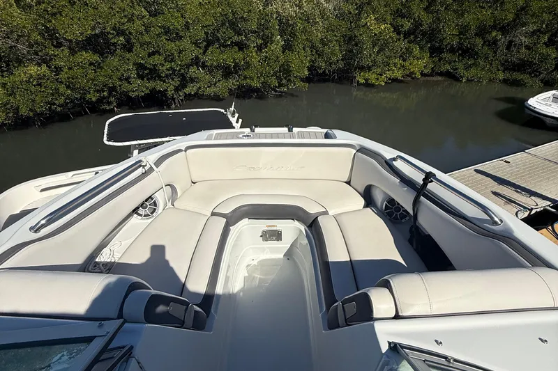 Slide: The Image of 2022 Crownline Eclipse E235 XS boat with spacious seating, docked near lush greenery. - 24