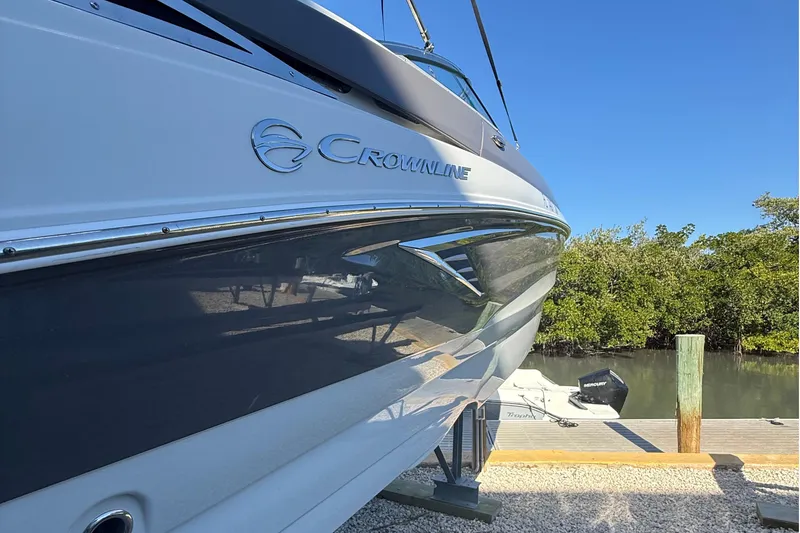 Slide: The Image of 2022 Crownline Eclipse E235 XS boat docked near lush greenery. - 4