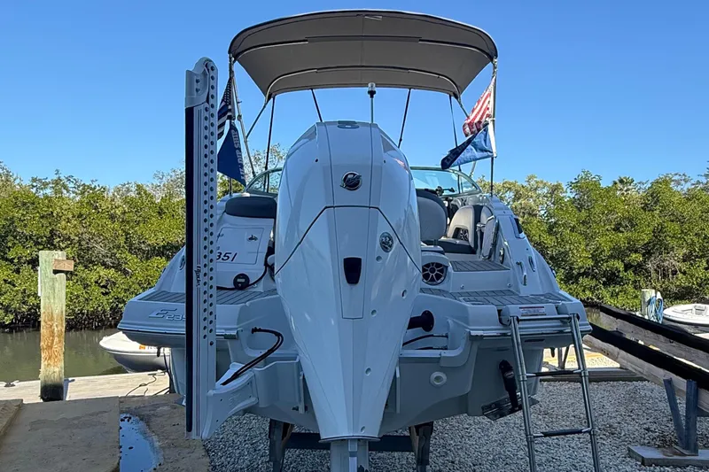 Slide: The Image of 2022 Crownline Eclipse E235 XS boat docked with canopy and flags. - 9