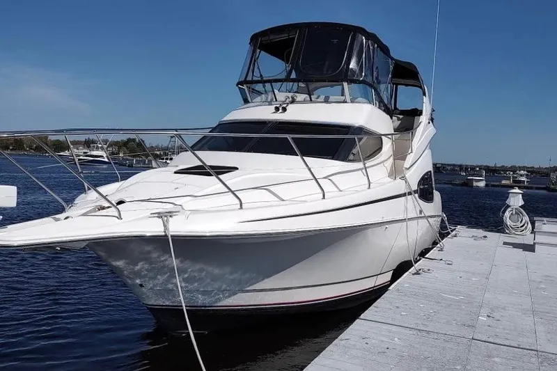 The Image of 2001 Silverton 330 Sport Bridge yacht docked at marina under clear blue sky. - 0
