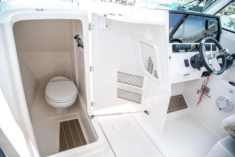 Slide: The Image of 2025 Sailfish 276 DC boat interior with helm and compact marine toilet. - 10