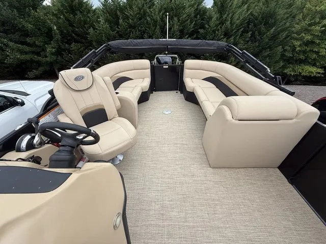Slide: The Image of 2020 Barletta Boats C20Q pontoon with beige seating and steering console, surrounded by greenery. - 5