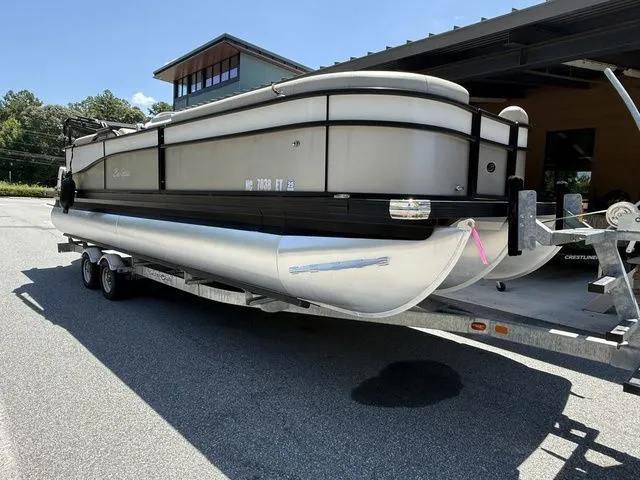 Slide: The Image of 2021 Barletta Boats C24Q pontoon on trailer, parked outdoors. - 2