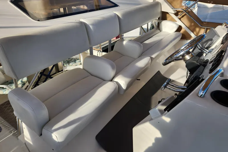 Slide: The Image of 2001 Silverton 392 Motor Yacht helm with white seating and steering wheel. - 12