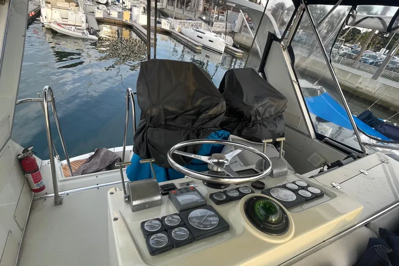 Slide: The Image of 1988 Tollycraft 34 Convertible Sedan helm with covered seats and marina view. - 4