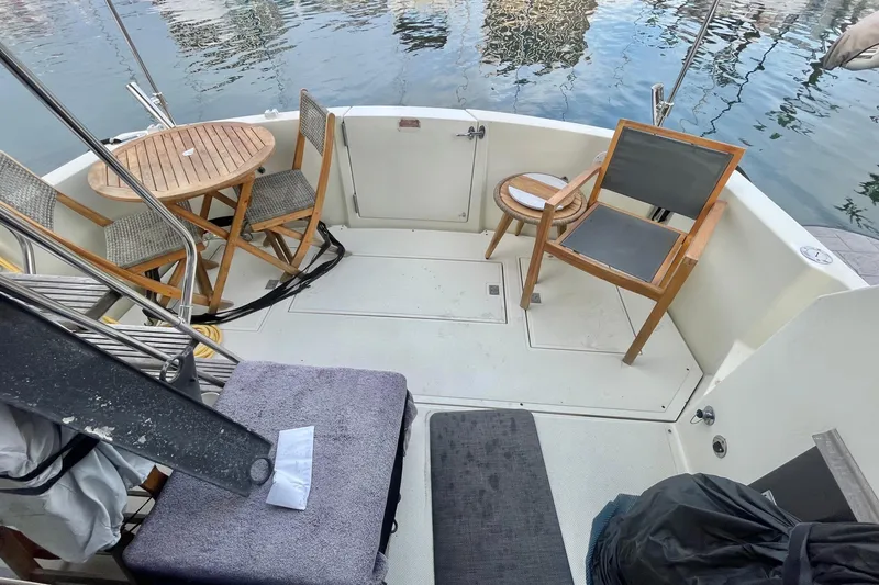 Slide: The Image of 1988 Tollycraft 34 Convertible Sedan boat deck with chairs and table by the water. - 6