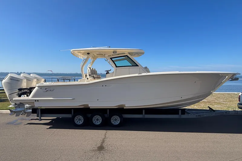 The Image of 2026 Scout 357 LXF boat on trailer by waterfront, clear sky background. - 0