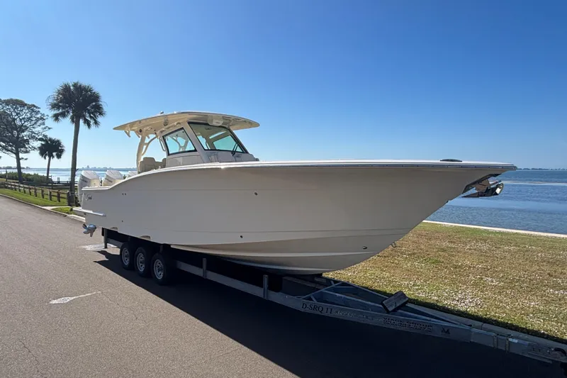 Slide: The Image of 2026 Scout 357 LXF boat on trailer by waterfront, clear blue sky. - 2