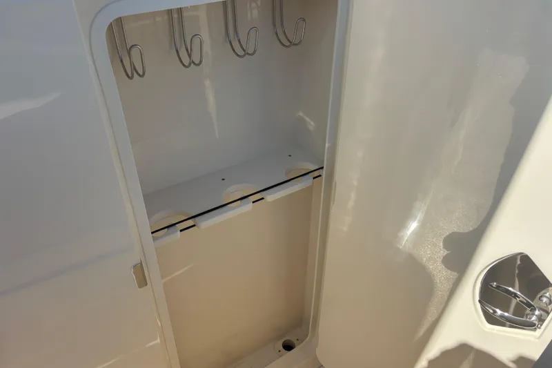 Slide: The Image of Storage compartment inside 2026 Scout 357 LXF boat, featuring hooks and cup holders. - 28