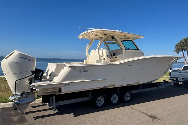 Slide: The Image of 2026 Scout 357 LXF boat on trailer by waterfront, featuring Mercury outboard engine. - 4