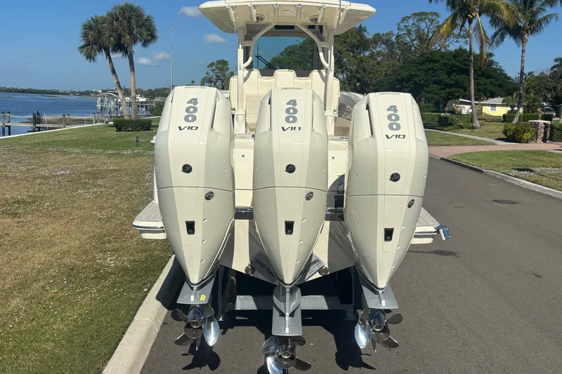Slide: The Image of 2026 Scout 357 LXF boat with triple Mercury 400 V10 engines, parked near waterfront. - 5