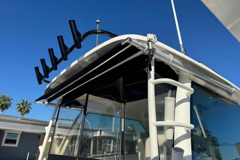 Slide: The Image of 2014 Boston Whaler 315 Conquest boat with  custom rod holders and ladder, under clear blue sky. - 10