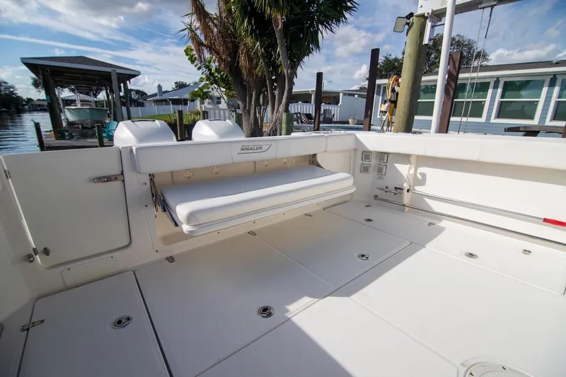 Slide: The Image of 2014 Boston Whaler 315 Conquest boat deck with seating, docked by waterfront homes. - 13