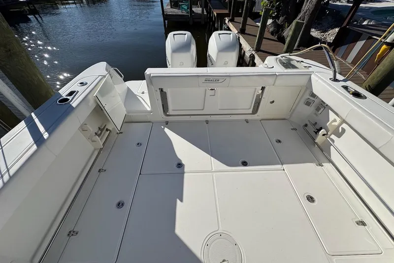 Slide: The Image of 2014 Boston Whaler 315 Conquest boat deck with twin engines, docked by the water. - 14