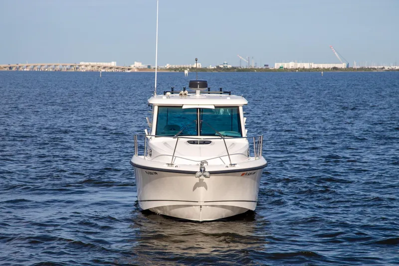 Slide: The Image of 2014 Boston Whaler 315 Conquest boat on open water, cityscape in background. - 2