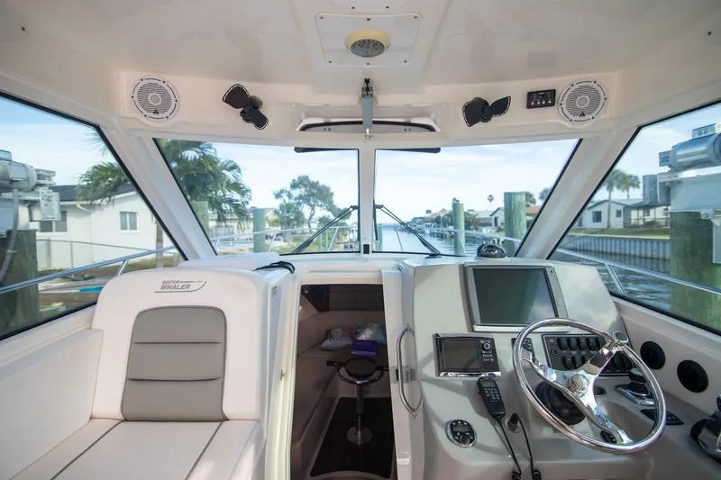 Slide: The Image of 2014 Boston Whaler 315 Conquest boat interior with steering wheel and navigation equipment. - 23