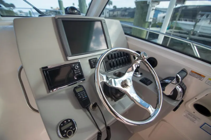 Slide: The Image of Helm of 2014 Boston Whaler 315 Conquest with steering wheel and navigation controls. - 25