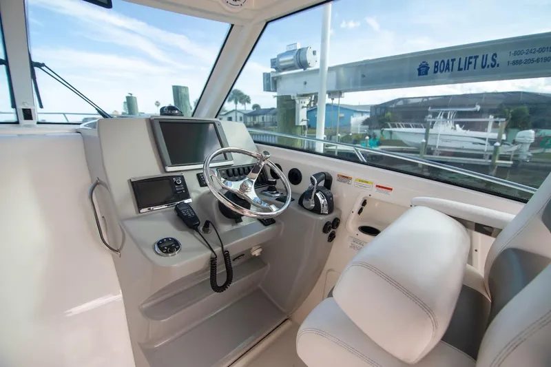 Slide: The Image of 2014 Boston Whaler 315 Conquest helm with steering wheel, controls, and navigation equipment. - 26