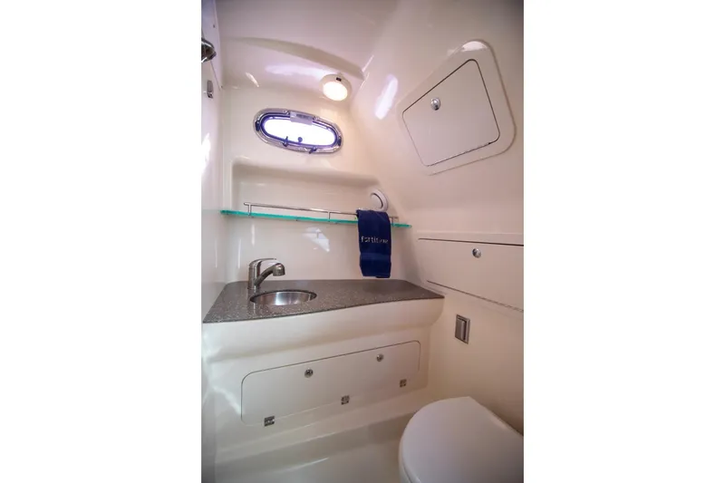 Slide: The Image of 2014 Boston Whaler 315 Conquest bathroom interior with sink, storage, and porthole window. - 33