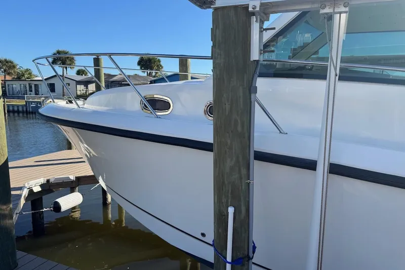 Slide: The Image of 2014 Boston Whaler 315 Conquest docked, showcasing sleek white hull and stainless steel railings. - 41