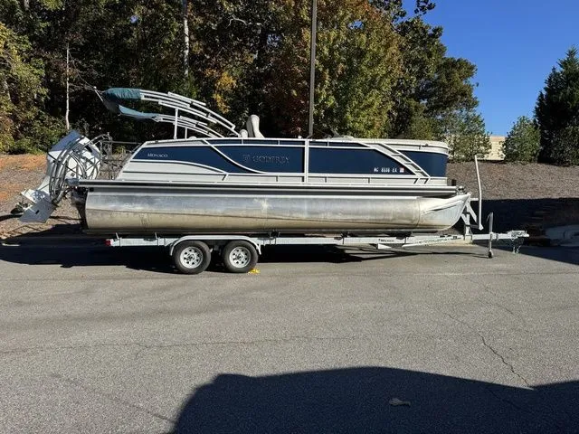 The Image of 2022 Godfrey Pontoons Monaco 235 on trailer, parked outdoors, surrounded by trees. - 1