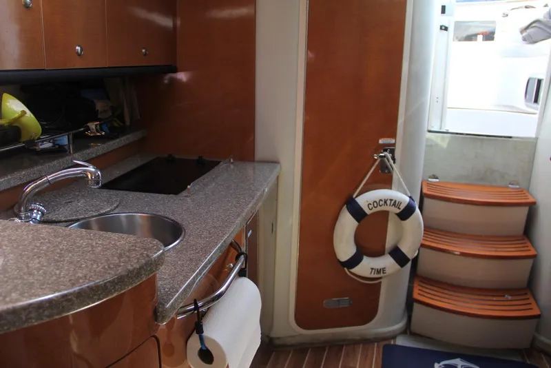 Slide: The Image of 2008 Chaparral Signature 330 yacht interior with kitchenette and stairs, featuring a "Cocktail Time" life preserver. - 21