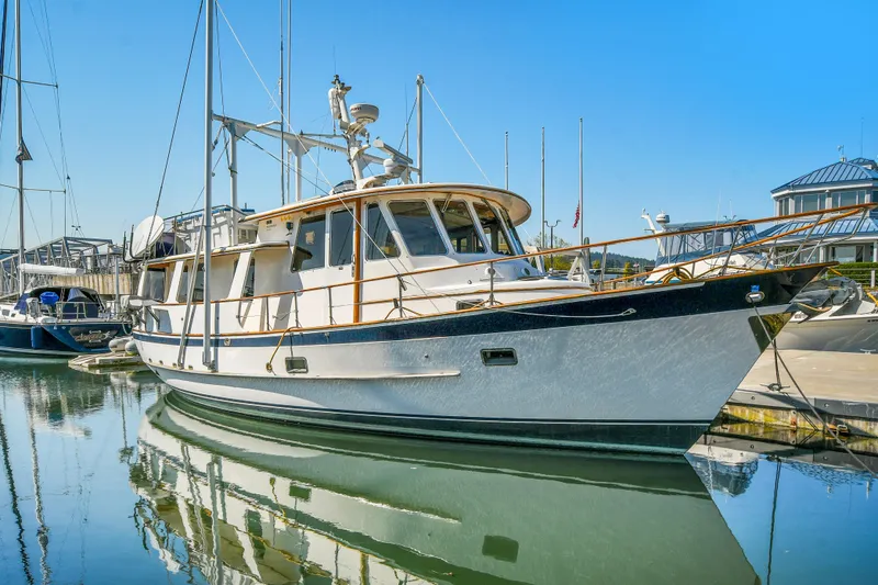 The Image of 1991 TransWorld Fantail 50 Motor Yacht docked in a marina, reflecting on calm water. - 0