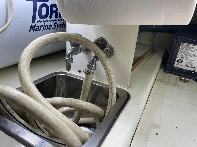 Slide: The Image of 1991 TransWorld Fantail 50 Motor Yacht sink with hoses and marine system components. - 31