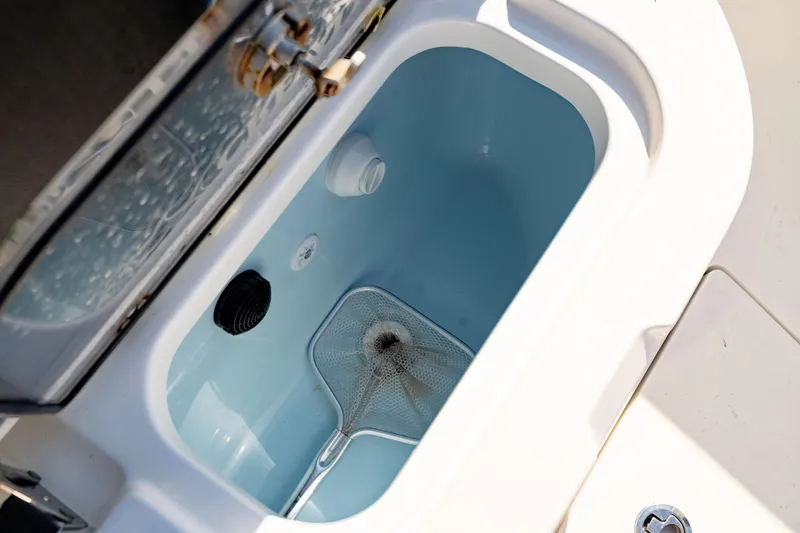 Slide: The Image of Livewell compartment on 2022 Crevalle 33 CSF boat, featuring a net and water aerator. - 32