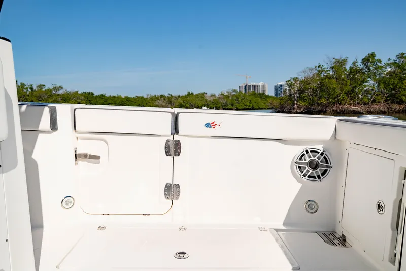 Slide: The Image of 2022 Crevalle 33 CSF boat interior with speaker and storage, surrounded by lush greenery. - 41