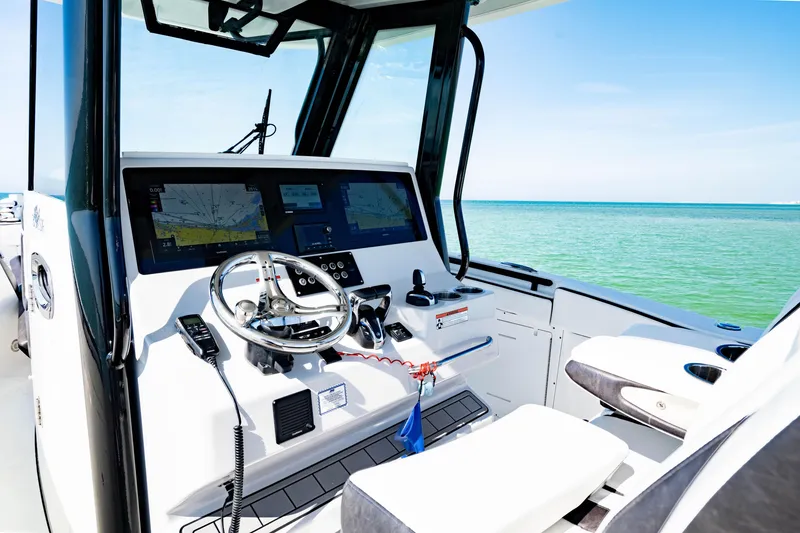 Slide: The Image of 2022 Crevalle 33 CSF boat helm with navigation screens, steering wheel, and ocean view. - 78