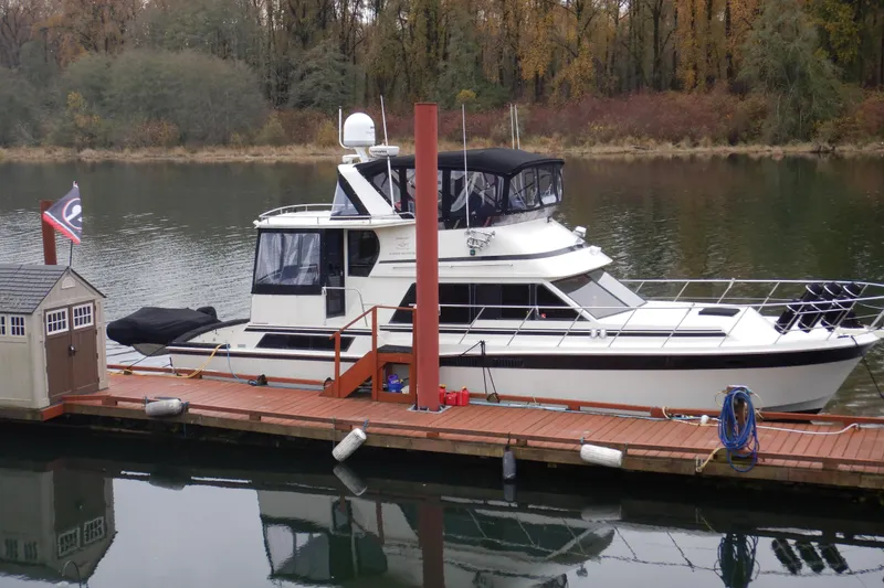 Slide: The Image of 1988 Camargue 48 Cockpit Motor Yacht docked on a serene river. - 2