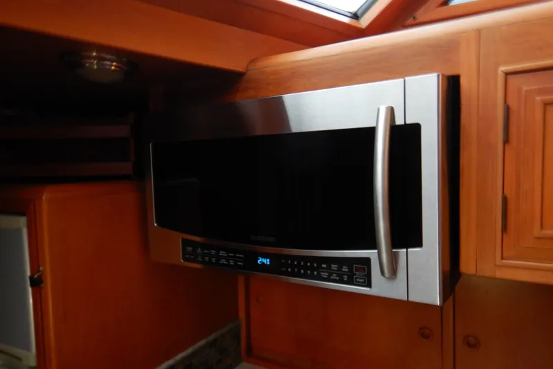 Slide: The Image of Microwave in 1988 Camargue 48 Cockpit Motor Yacht kitchen, featuring wooden cabinetry. - 32