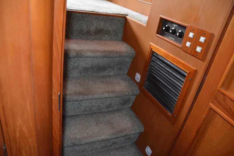 Slide: The Image of Carpeted stairs inside 1988 Camargue 48 Cockpit Motor Yacht with wooden paneling and control switches. - 37
