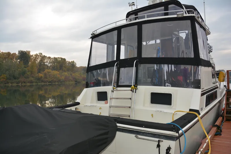 Slide: The Image of 1988 Camargue 48 Cockpit Motor Yacht docked by a serene riverbank. - 4
