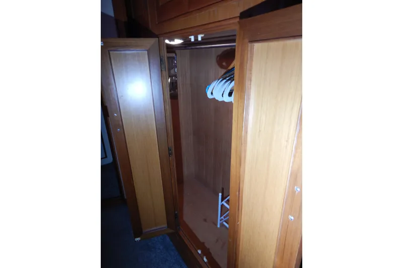 Slide: The Image of Wooden closet interior on 1988 Camargue 48 Cockpit Motor Yacht, featuring hangers and storage space. - 48