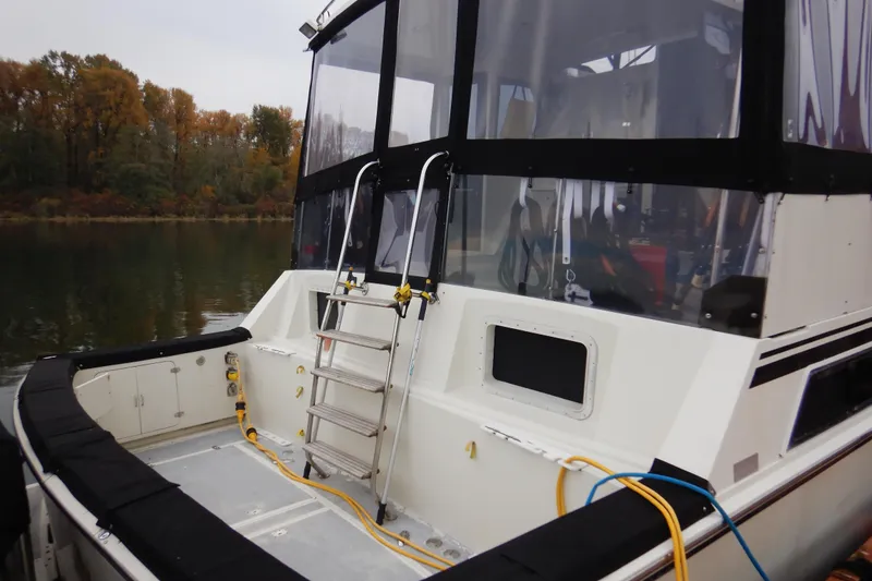 Slide: The Image of 1988 Camargue 48 Cockpit Motor Yacht with ladder and cables, docked by autumn trees. - 5