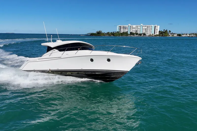 Slide: The Image of 2023 Tiara Yachts C39 Coupe cruising on blue ocean near coastal buildings. - 29