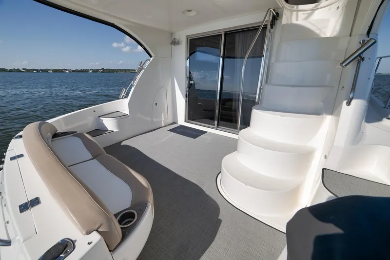 Slide: The Image of 2012 Meridian 441 Sedan yacht interior with seating and stairs, overlooking calm waters. - 79