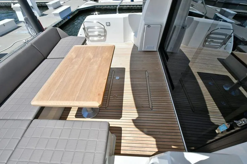 Slide: The Image of 2019 Prestige 460 yacht deck with wooden table and cushioned seating. - 34