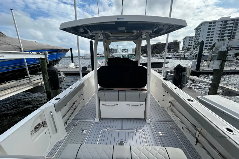 Slide: The Image of 2023 Pursuit S 288 Sport boat interior at marina, showcasing seating and deck layout. - 11