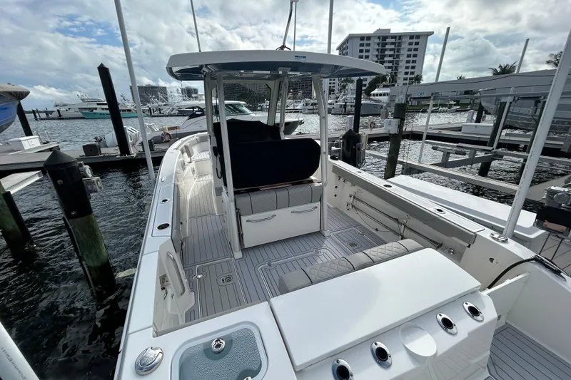 Slide: The Image of 2023 Pursuit S 288 Sport boat docked at marina, showcasing spacious deck and seating. - 13