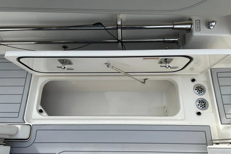 Slide: The Image of 2023 Pursuit S 288 Sport boat storage compartment with open lid and drainage system. - 17