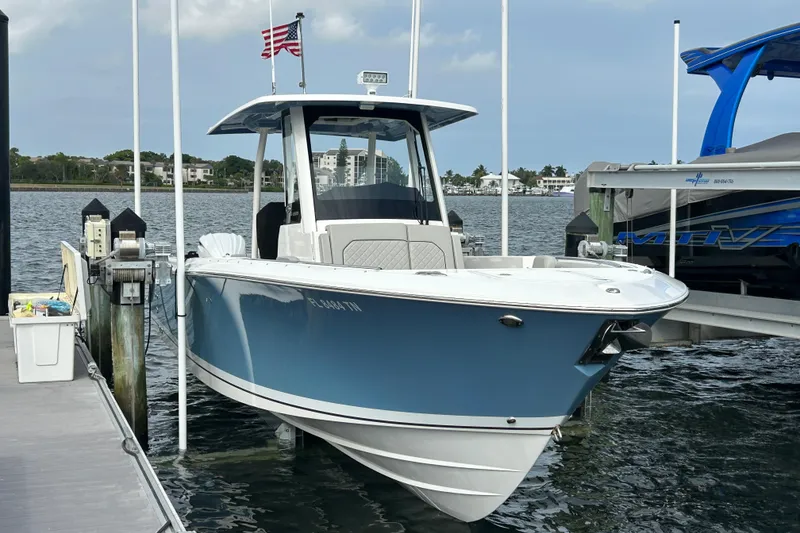 Slide: The Image of 2023 Pursuit S 288 Sport boat docked with American flag, calm waters. - 2