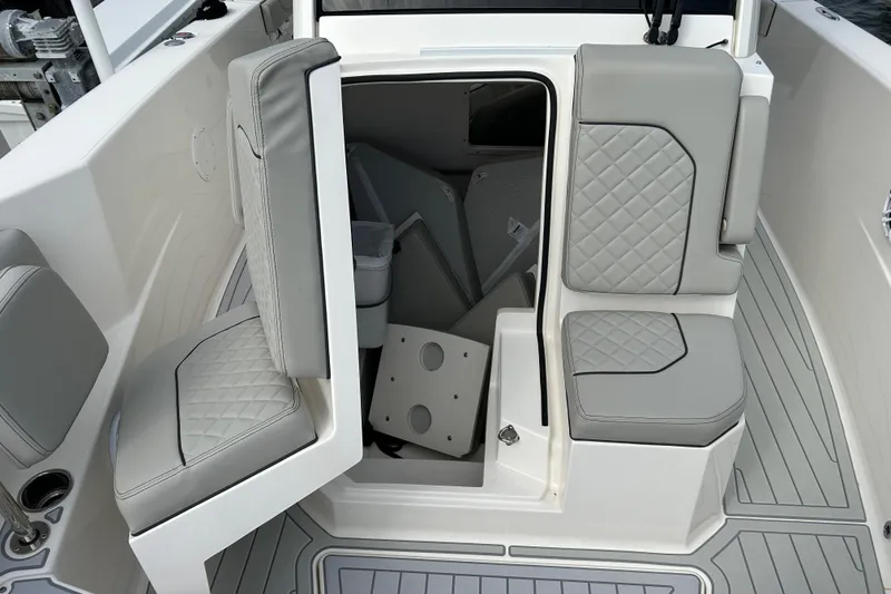 Slide: The Image of 2023 Pursuit S 288 Sport boat interior with gray cushioned seating and storage access. - 38