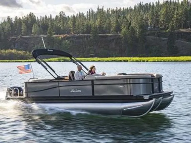 The Image of 2026 Barletta Cabrio 22M pontoon boat cruising on a scenic lake with forested background. - 0