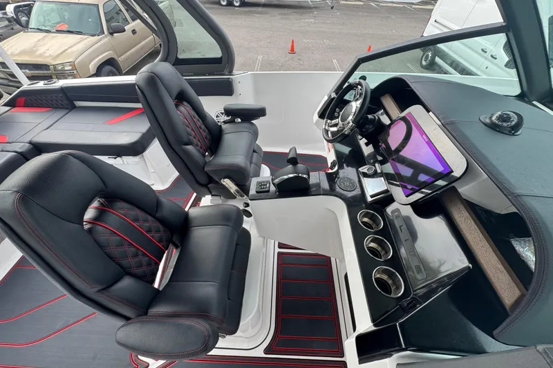 Slide: The Image of 2025 Monterey Elite 27 OB boat interior with black and red seating, modern dashboard, and steering wheel. - 24