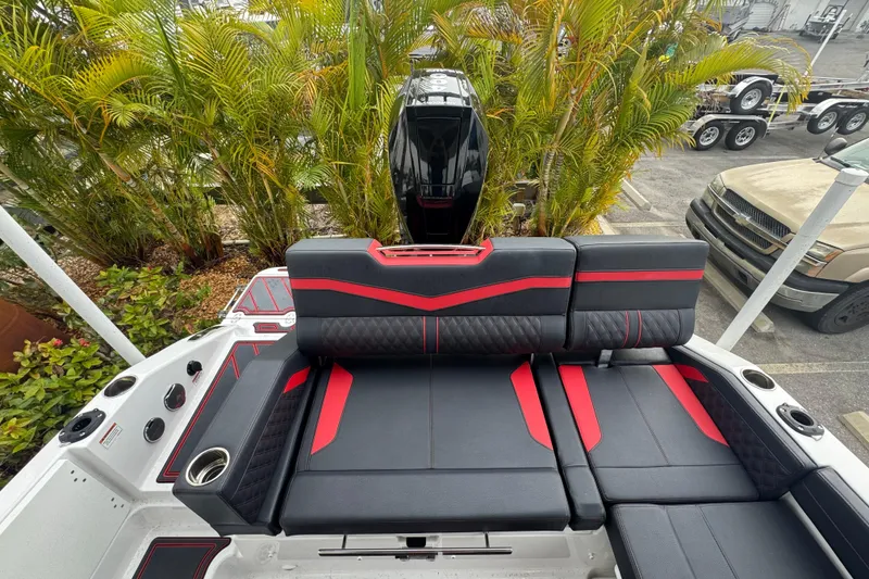 Slide: The Image of 2025 Monterey Elite 27 OB boat with stylish black and red seating, surrounded by lush greenery. - 36