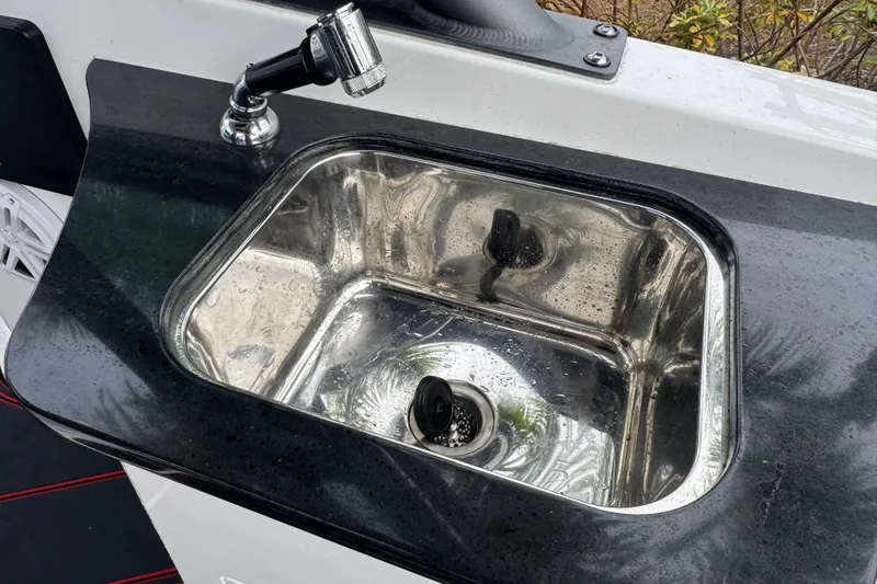 Slide: The Image of Stainless steel sink on 2025 Monterey Elite 27 OB boat with sleek black countertop. - 37
