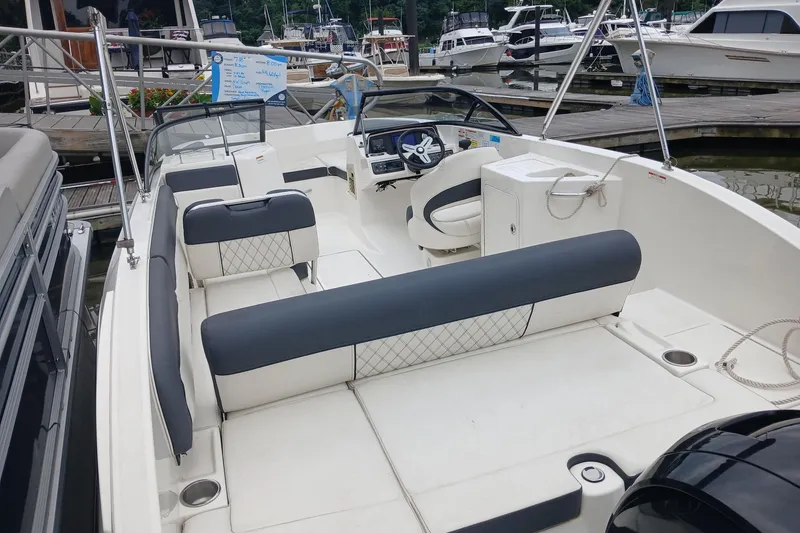 Slide: The Image of 2023 Bayliner DX 2200 boat interior with seating and steering wheel at marina. - 10
